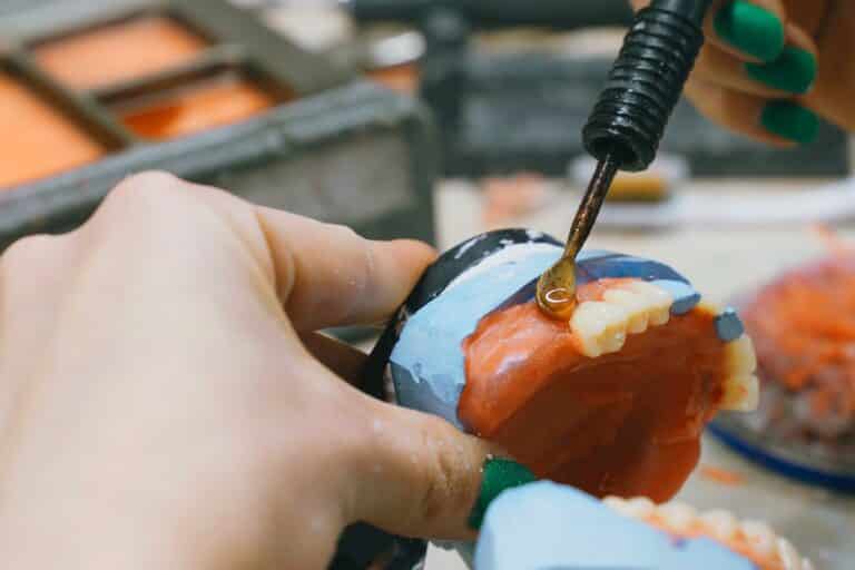 A dental technician meticulously works on repairing dentures using specialized tools and techniques to ensure precision and quality