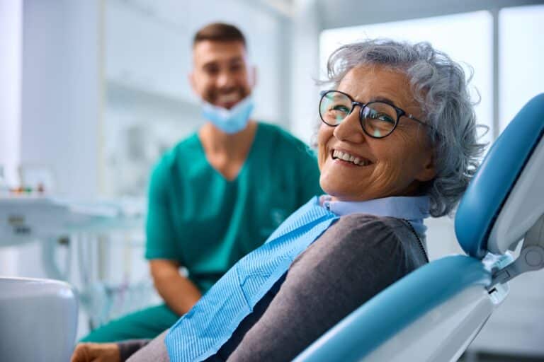 older woman smiling in a dental office, new dentures